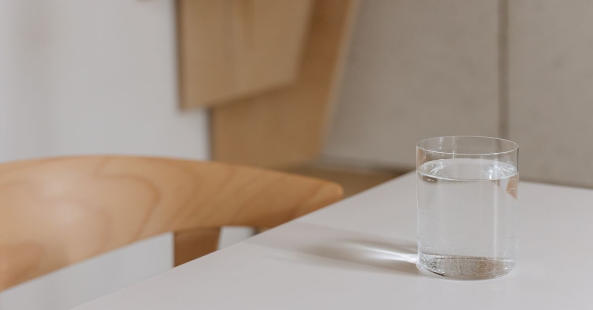 Simple and elegant composition of a water glass on a modern wooden table indoors.