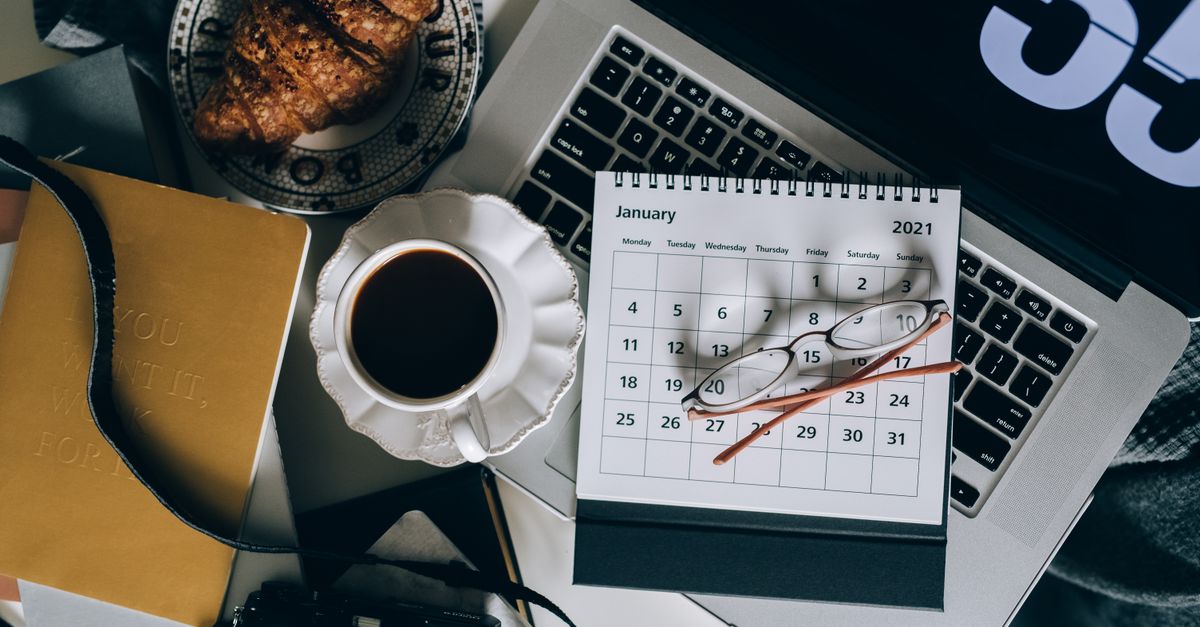 A serene workspace setup with coffee, croissant, laptop, and calendar, ideal for organizing plans.