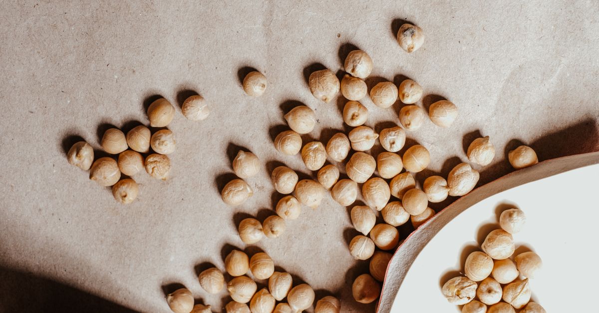 Close-up of dried chickpeas scattered on a textured brown surface, perfect for healthy food imagery.